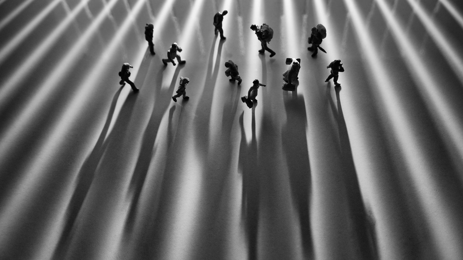 Miniature toys studio set up - Top view of black and white effect of people with long shadows busy walking during sunrise or sunset. Noise added for dramatic effect.