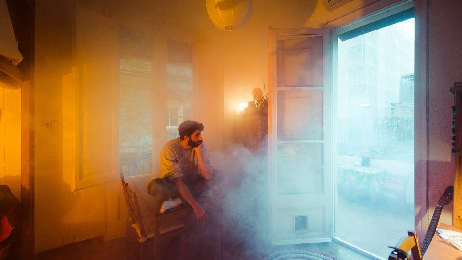Surreal portrait of sitting man in burning home